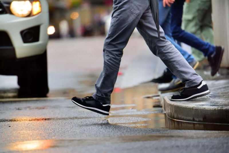Close up of pedestrians stepping off the sidewalk to cross a city street.